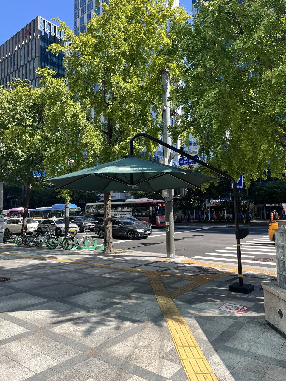 Large shade umbrellas set up where pedestrians wait at a crossing