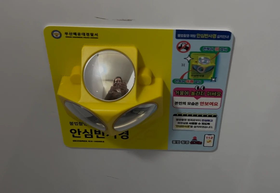 Small three-angle mirror mounted inside a public toilet stall in Gyeongju
